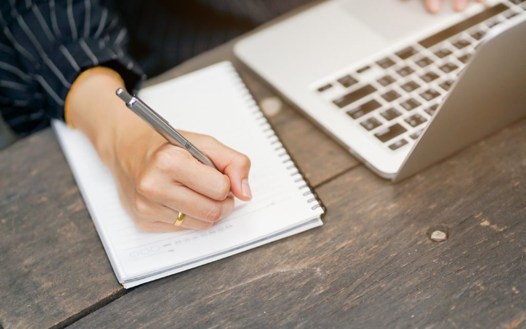 Woman writes scripted outline in notebook