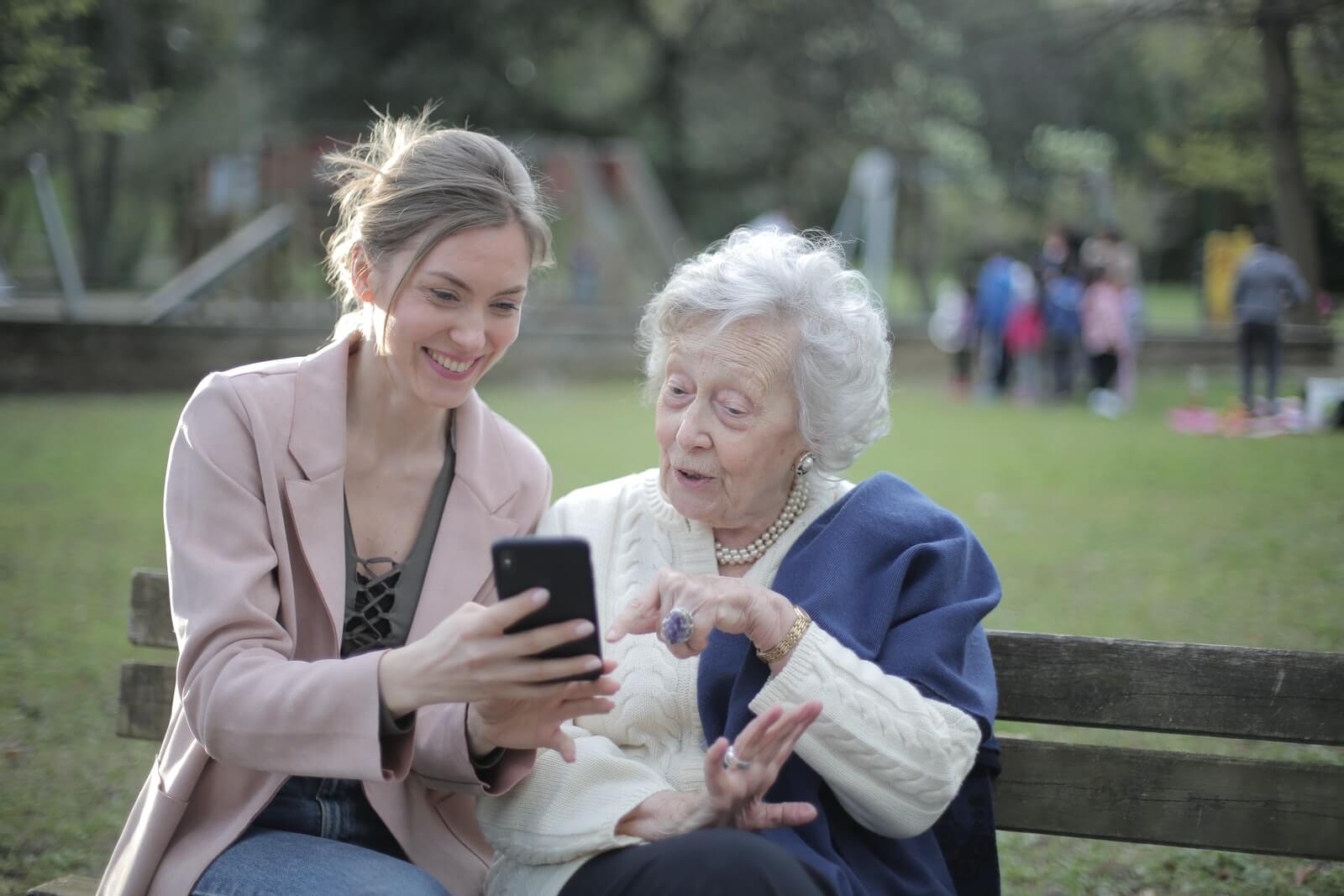 A senior citizen's adult daughter shows her the website of a senior living community on her smart phone.